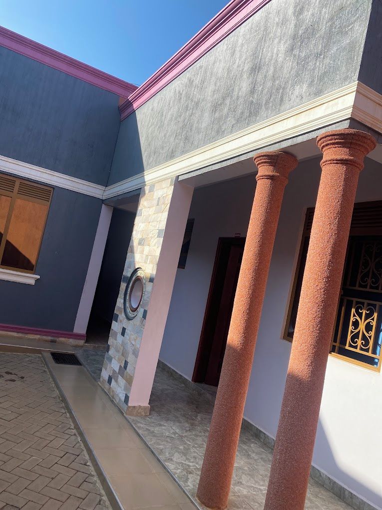 Un edificio con un acceso cubierto, columnas y un muro con diseño.