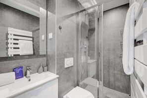 A modern bathroom with a glass shower enclosure, a white sink, and a large mirror. - Spacious Apartment- 3br/6p - Charenton (Charenton-le-Pont)