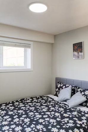 A bedroom with a bed, a window, and a wall-mounted picture.