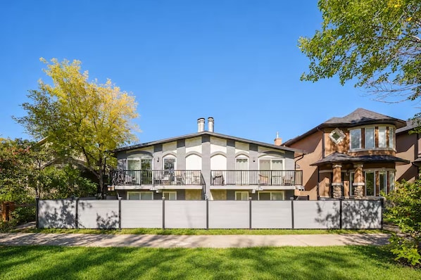 A two-story house with a balcony, a garage, and a well-maintained lawn.