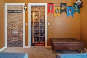 Een kamer met een boekenkast, een bank en een muur met vlaggen.
