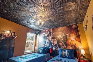 Een kamer met een plafond vol gedetailleerde patronen, een groot muurschilderij en twee bedden met bijpassende kussens.