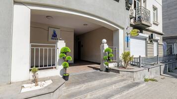 A building entrance with a curved overhang, a signboard, and a gated entrance.