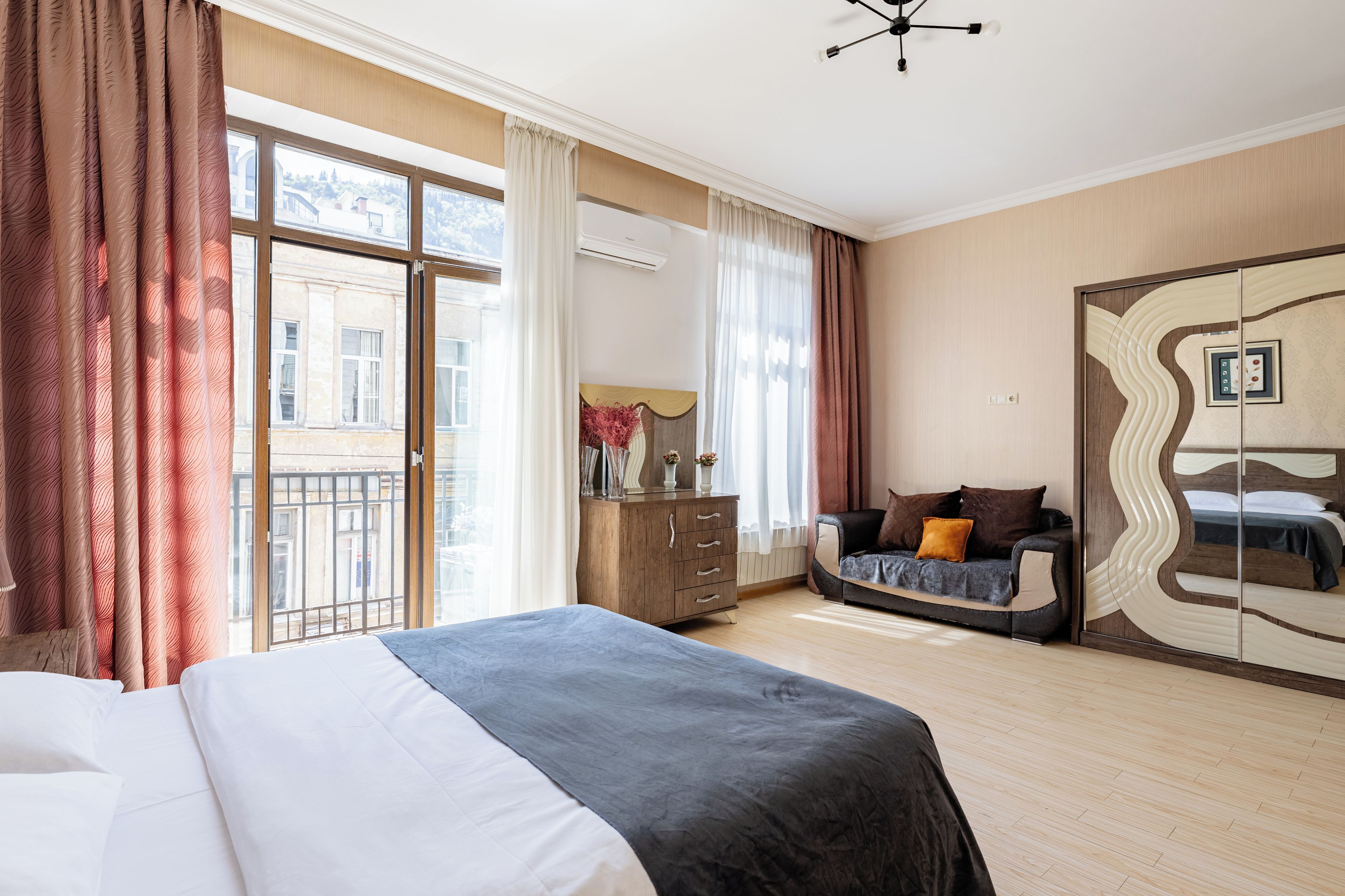 A hotel room with a large bed, a sofa, a dresser, and a wardrobe.