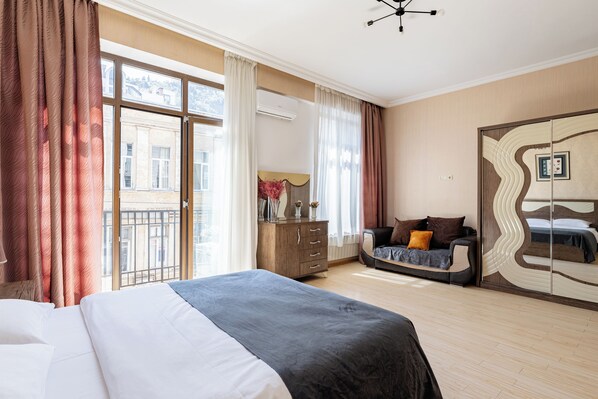 Una habitación de hotel con una cama grande, un sofá, un aparador y un armario.