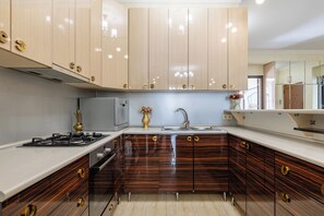 Una cocina moderna con armarios de madera, estufa a gas y pileta de acero inoxidable.