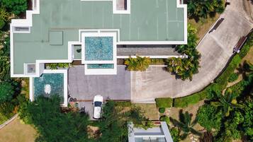 Vista aérea de una casa moderna con piscina, camino de entrada y vegetación circundante.