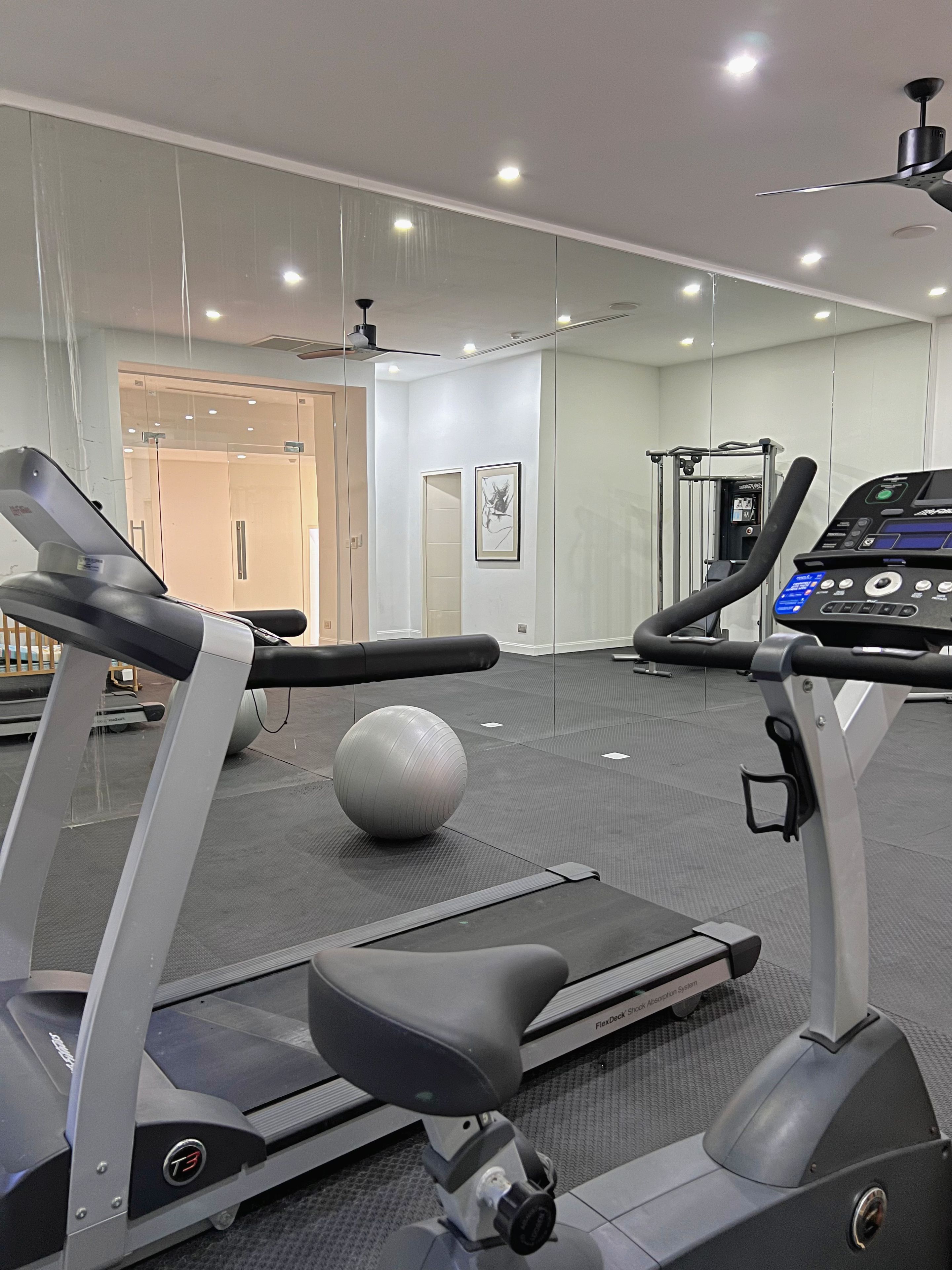 Un gimnasio con cintas de correr, una bicicleta estática y una máquina de remo.