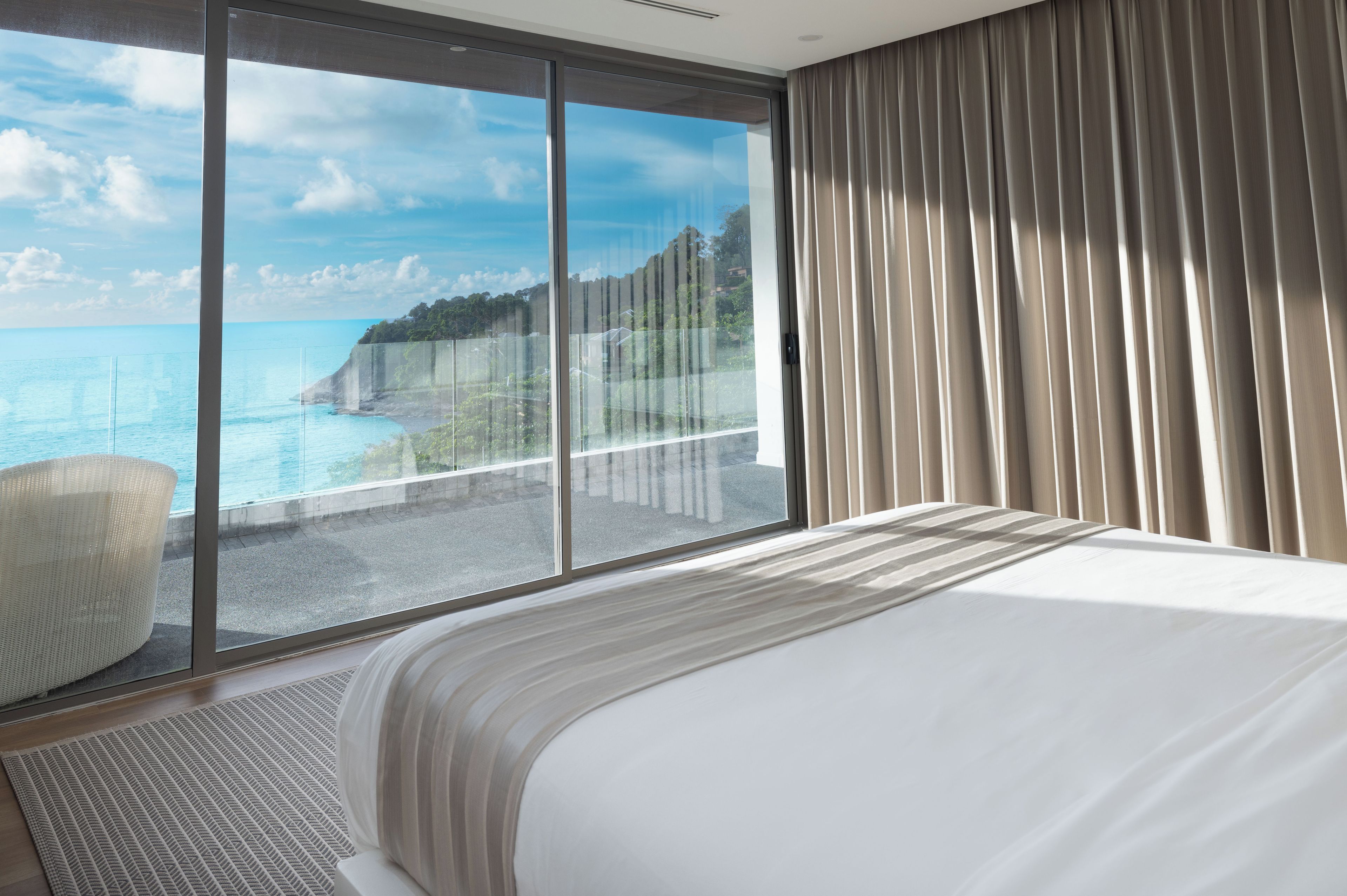 Habitación de hotel con un ventanal que ofrece vistas al mar y un balcón.