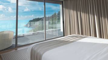 Habitación de hotel con un ventanal que ofrece vistas al mar y un balcón.