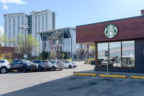 En Starbucks Coffee butik med et moderne design, beliggende i en parkeringsplads med flere biler.