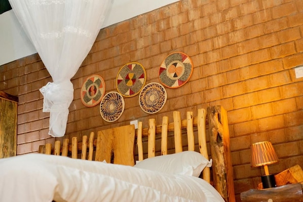 A bed with white bedding, a wooden headboard, and a wall with woven wall art.