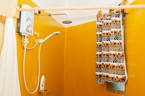 A bathroom with a yellow wall, a shower with a white hose, and a towel rack with a patterned towel.