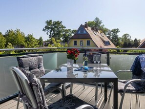 A glass-enclosed balcony with a table, chairs, and a bottle of wine. - Holiday Apartment With 1 Bedroom (Zingst)