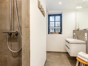 A modern bathroom with a shower, a window, a sink, and a towel rack. - Holiday Apartment With 1 Bedroom (Zingst)
