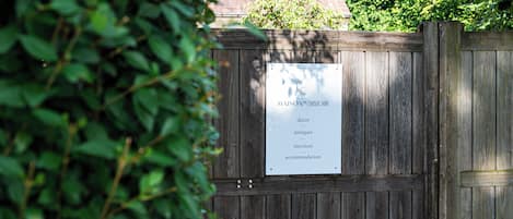 A wooden gate with a sign listing services like decor, antiques, interiors, and accommodation.