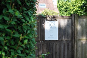 A wooden gate with a sign listing services like decor, antiques, interiors, and accommodation. - New Listing (Deurle)