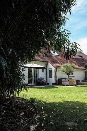 A house with a tiled roof, a covered patio, and a lawn. - New Listing (Deurle)