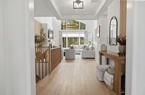 A modern interior with a wooden floor, white walls, a sofa set, and a chandelier. - Muskoka Pines -Private Oasis Spa- Hot Tub & Sauna (Lake of Bays)