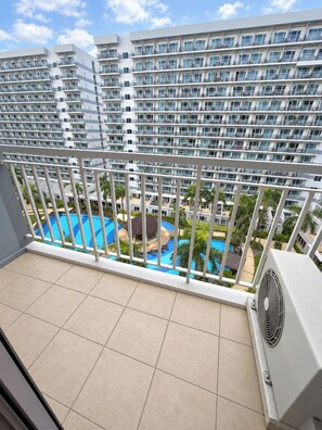 Ein Balkon mit Blick auf einen Swimmingpool und hohe Gebäude.