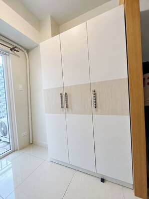 A large wardrobe with a sliding door, a visible power outlet, and a clean, tiled floor. - Zen Escape 1Br with Balcony pacing pool (Pasay City)