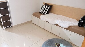 A clean, modern room with a sofa bed, a small round rug, and a storage unit. - Zen Escape 1Br with Balcony pacing pool (Pasay City)