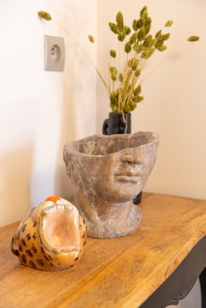 Una mesa de madera rústica con un bol de piedra y un florero de vidrio con plantas secas.