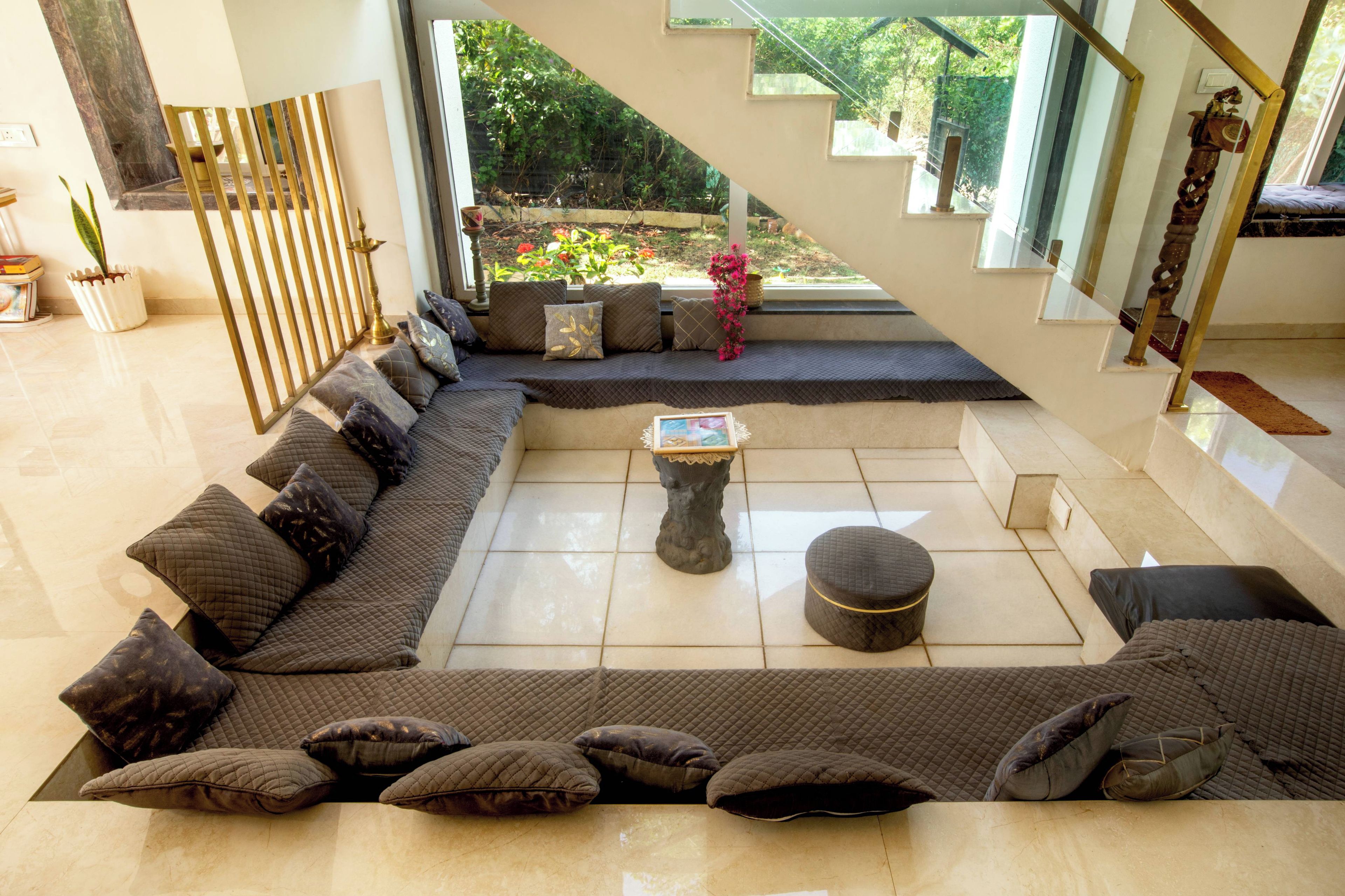 A spacious living area with a large sectional sofa, a coffee table, and a staircase leading to an outdoor garden.