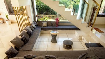A spacious living area with a large sectional sofa, a coffee table, and a staircase leading to an outdoor garden.