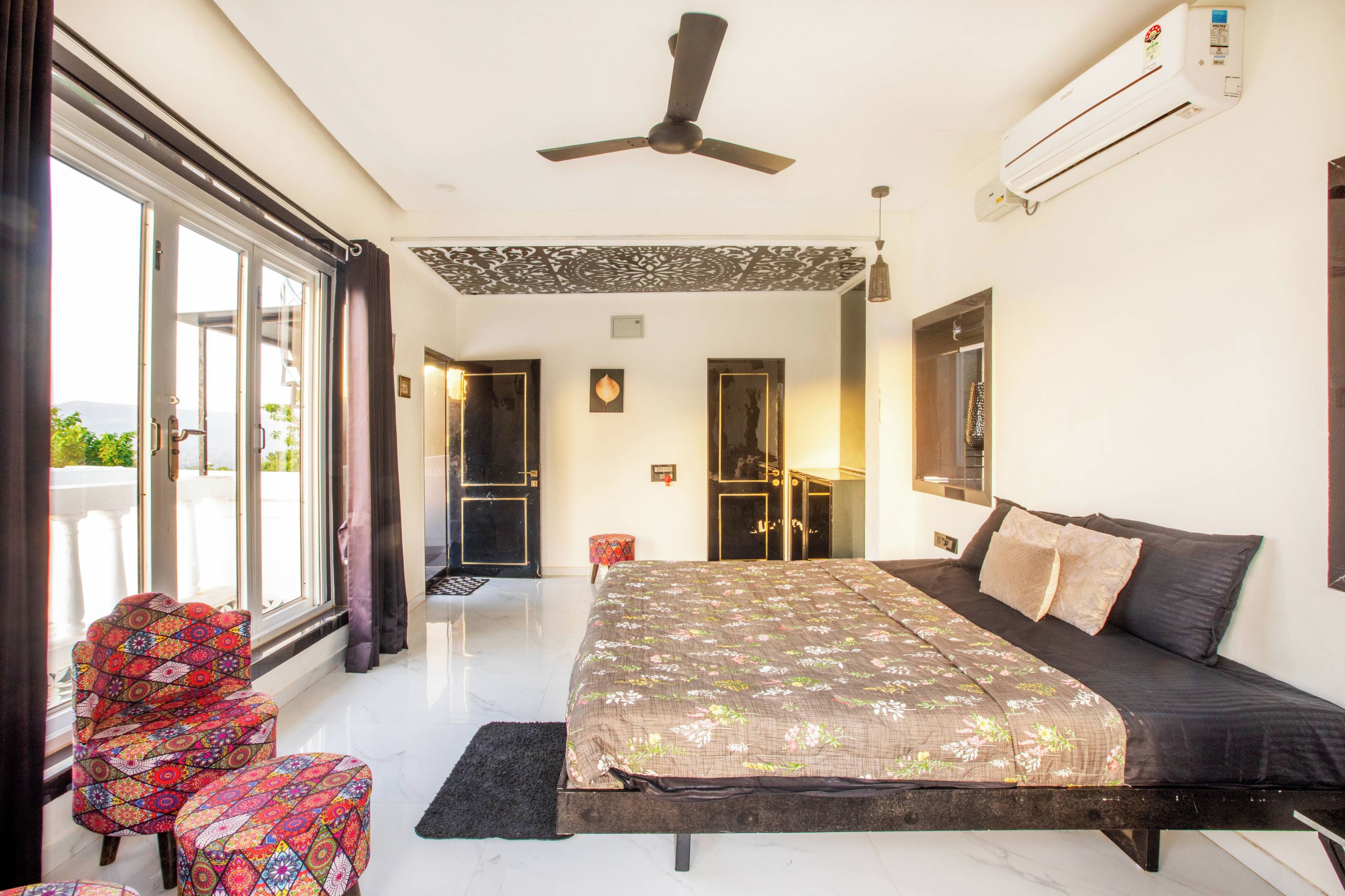 Habitación de hotel con cama, una silla, ventilador de techo, aire acondicionado y vista al exterior.