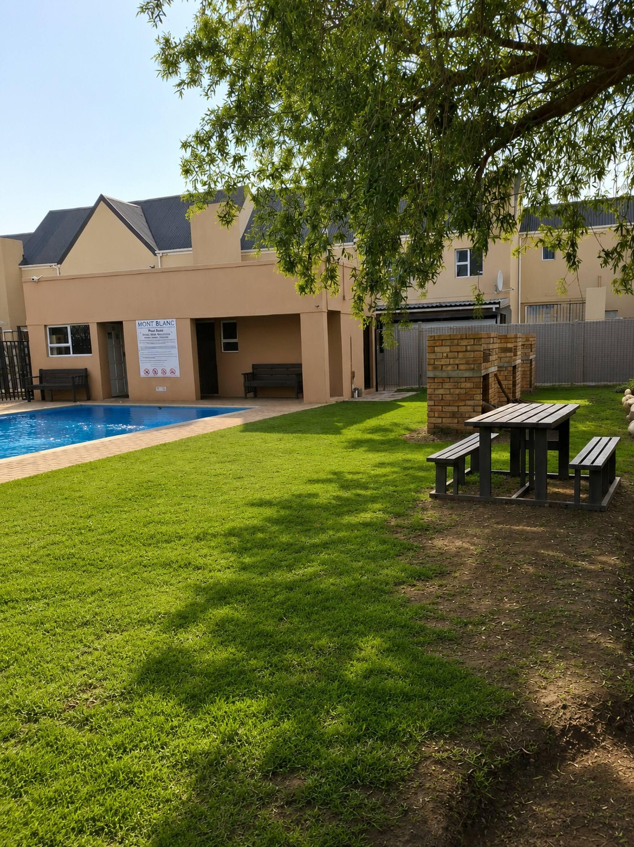 A residential property with a swimming pool, a barbecue area, and a well-maintained lawn.