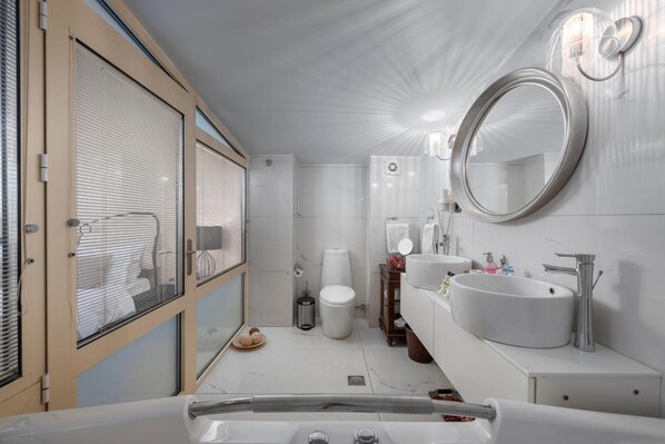 A modern bathroom with a large bathtub, two sinks, a toilet, and a shower. - Habitat Hotel Kilkis (Kilkis)