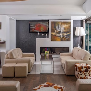 A modern living room with a fireplace, two sofas, a coffee table, and a large abstract painting. - Habitat Hotel Kilkis (Kilkis)