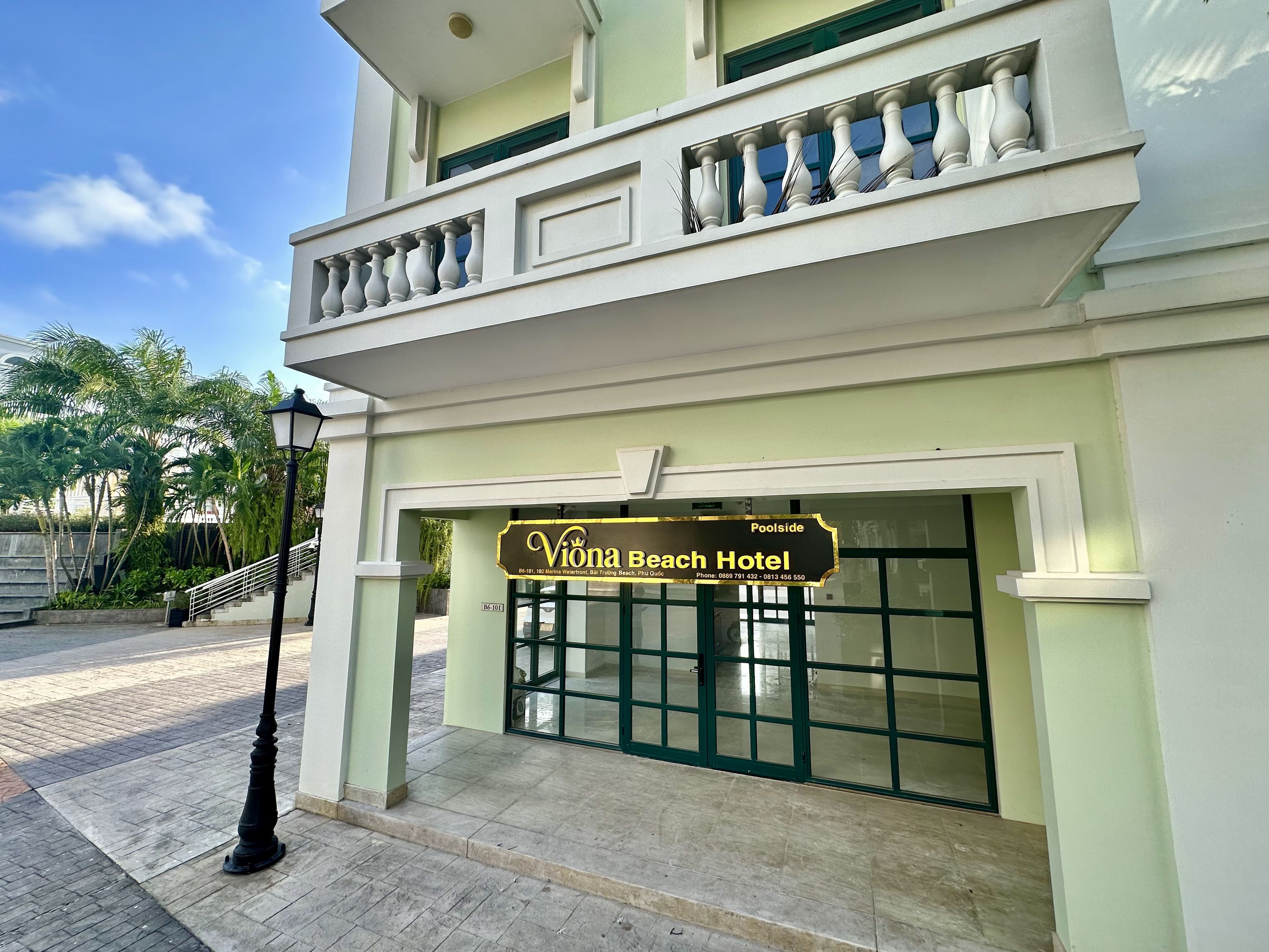 The exterior of Viona Beach Hotel with a clear entrance, a balcony with balustrades, and a street lamp.