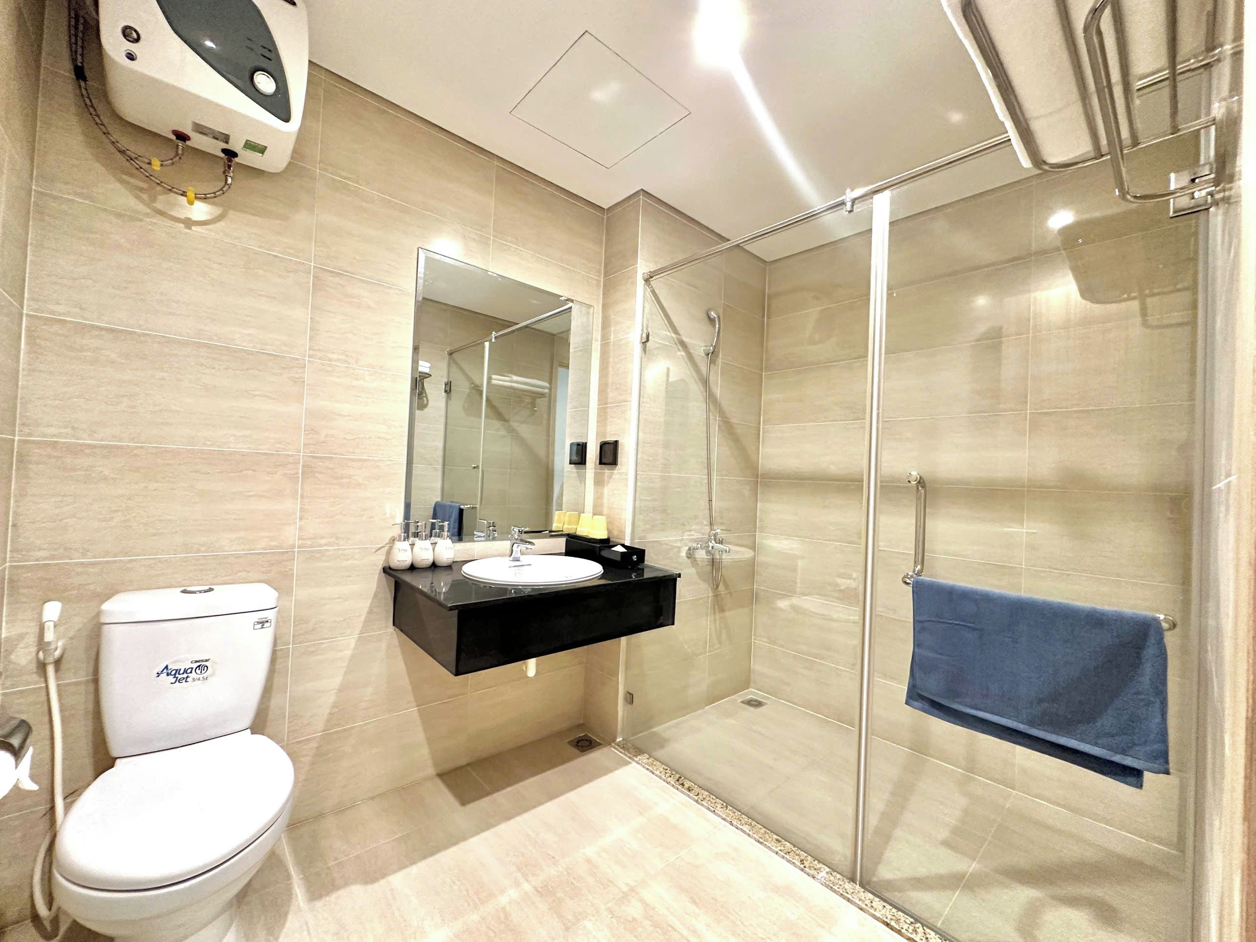 A modern bathroom with a toilet, sink, mirror, and glass-enclosed shower area.