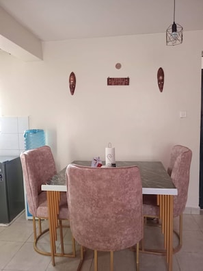 A dining area with a table and chairs, a water dispenser, and wall decorations. - Cozy 1-bedroom apartment with AC in wonderful Nairobi with JKIA and Park (Nairobi)