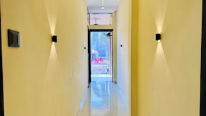 A hallway with a door leading to an outdoor area with chairs and a table. - Hotel Rishant Palace (Khandwa)