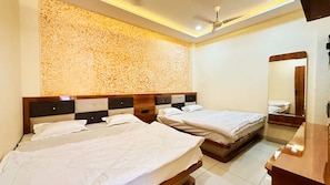 A hotel room with two beds, a ceiling fan, and a large mirror. - Hotel Rishant Palace (Omkareshwar)