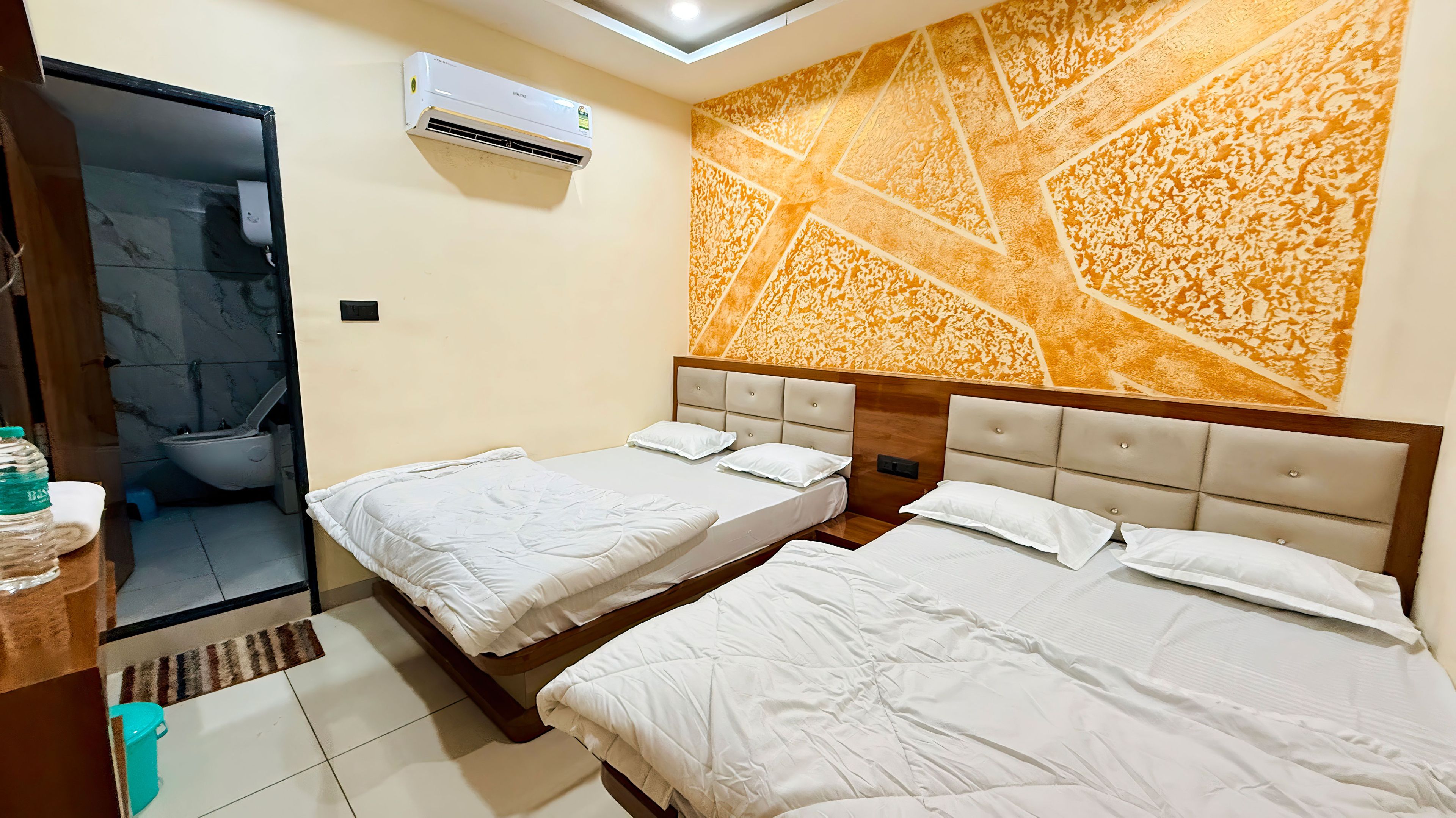 Habitación de hotel con dos camas, un baño y un adornado en la pared.