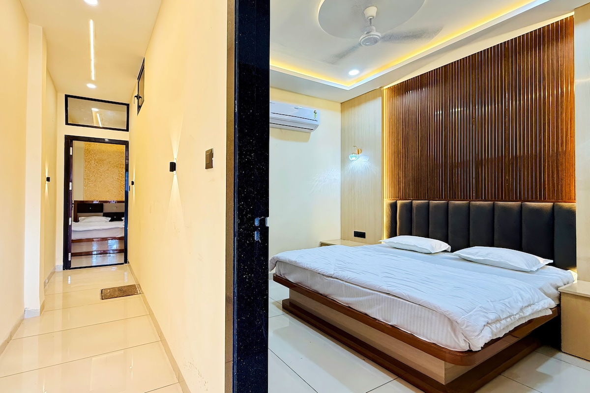 A hotel room with a bed, a ceiling fan, and a wall-mounted air conditioning unit.