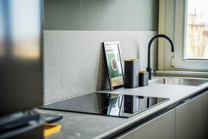 A kitchen with a black countertop, a stainless steel sink, and a framed coffee maker on the wall. - Comfy and cozy, at a short distance form sea, city centre and train station. (Rimini)
