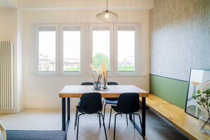 A dining area with a table, chairs, a vase with plants, and a window with a view of buildings. - Comfy and cozy, at a short distance form sea, city centre and train station. (Rimini)