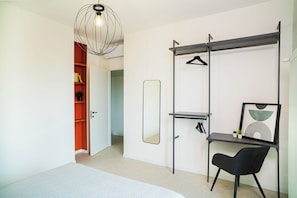 A modern bedroom with a bed, a desk, a chair, a wardrobe, a mirror, and a pendant light. - Comfy and cozy, at a short distance form sea, city centre and train station. (Rimini)