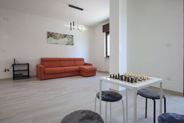 Un salon moderne avec un canapé, une table d’échecs et un tableau accroché au mur.