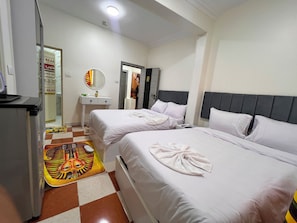Ein Hotelzimmer mit zwei Betten, einem kleinen Schreibtisch, einem Spiegel und einem karierten Boden.