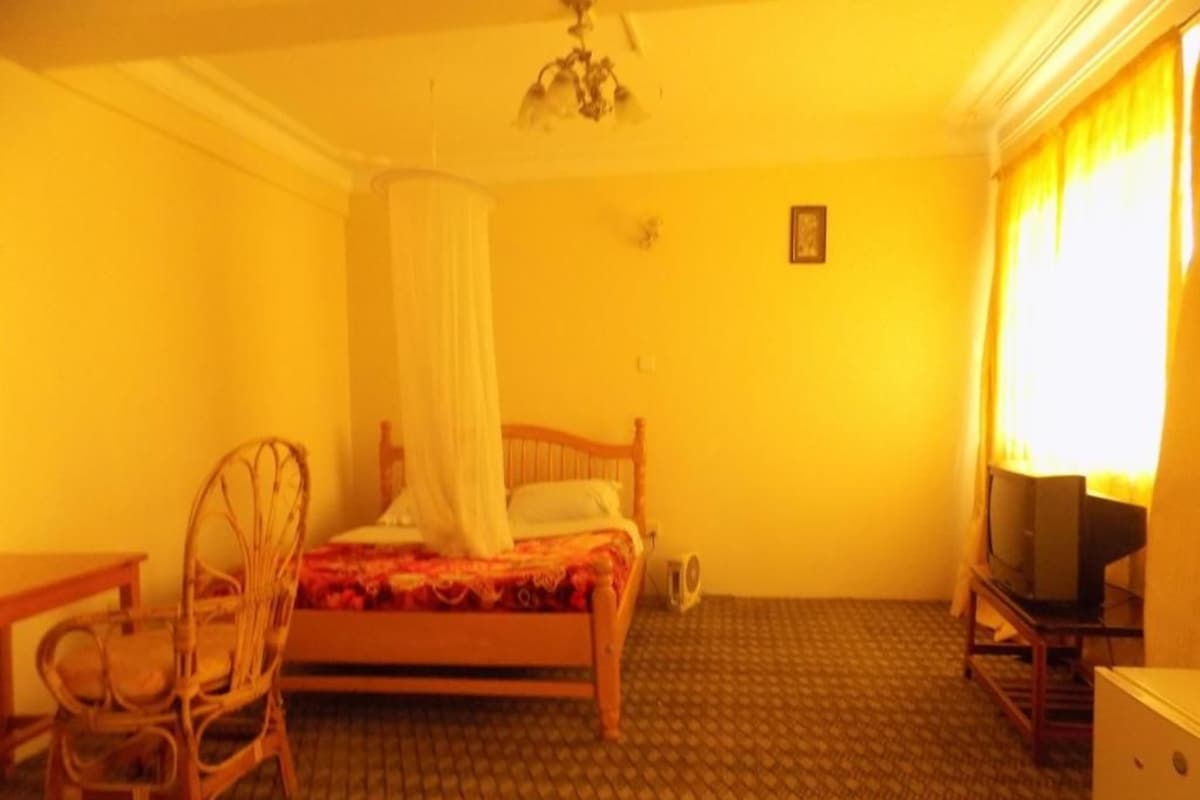 A room with a bed, a chair, a television, and a small table.