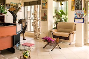 A well-lit living room with a leather sofa, a glass coffee table with flowers, a desk with a computer, and decorative items. - Meliva Guest House Mbarara (Mbarara)