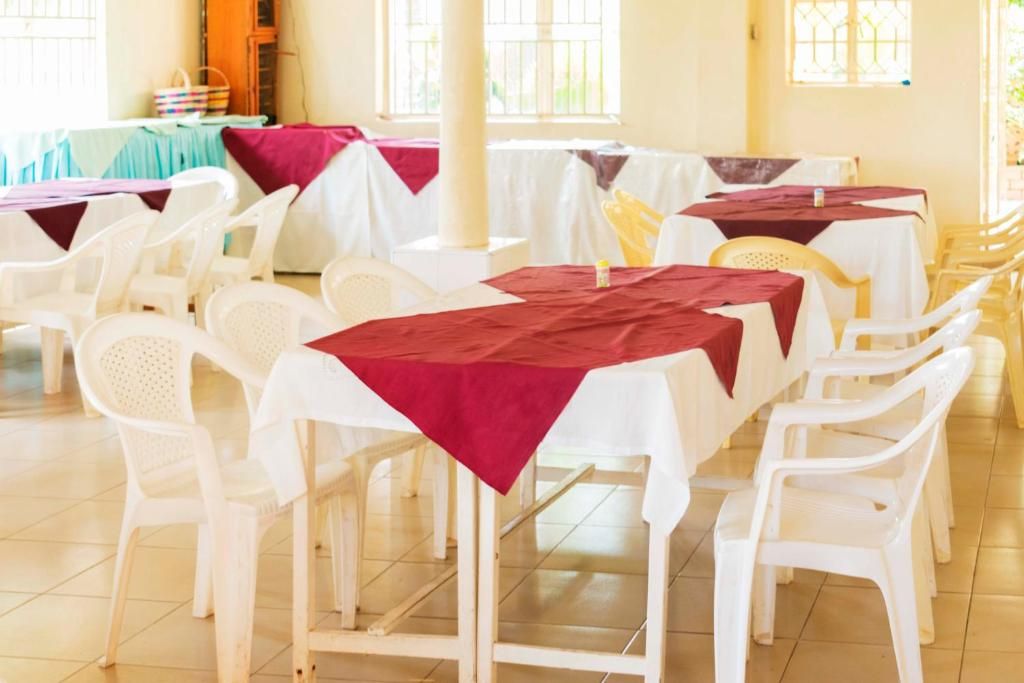 A room with multiple tables and chairs, arranged in rows.