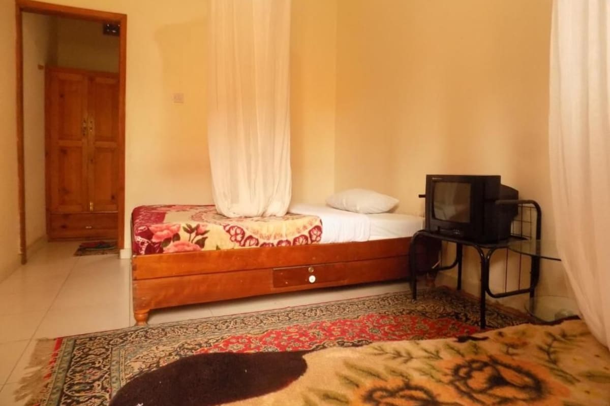 A bedroom with a bed, a television, and a wardrobe.