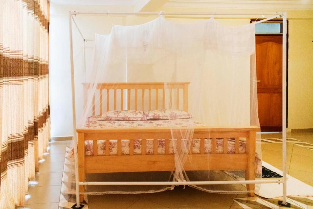 A bed with a mosquito net, wooden headboard, and floral bedding.